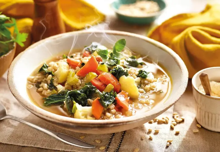 Un humeante tazón de sopa de cebada con kale, zanahorias y patatas. ¡Perfecto para tus recetas con kale!