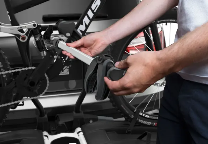 Hände montieren Fahrrad am Thule EasyFold XT 2. Ein Griff klemmt, was auf Thule EasyFold XT 2 Probleme hindeuten könnte.