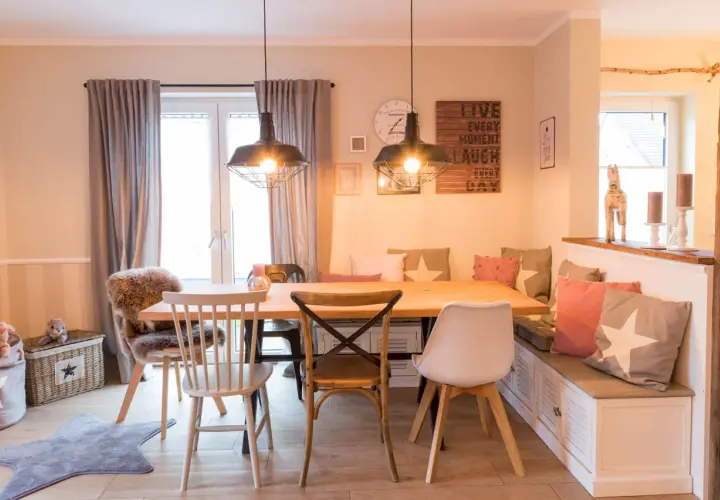 Gemütliches Esszimmer gestalten: Holztisch, Bank mit Kissen, verschiedene Stühle und Wanddeko schaffen einladendes Ambiente.