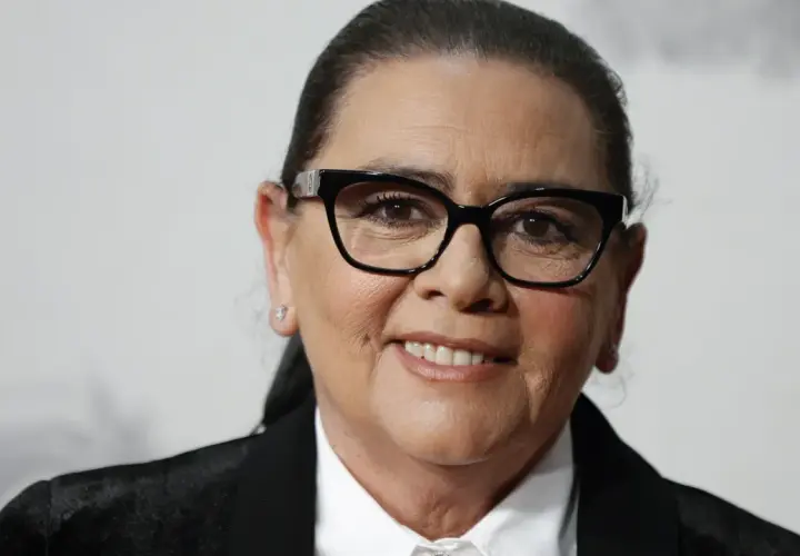 María del Monte, con gafas negras y una sonrisa amable, luce un traje elegante.
