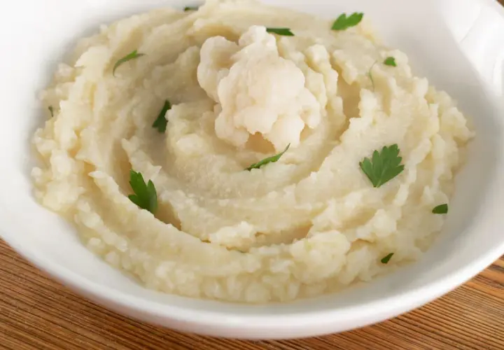 Aksamitne puree z kalafiora, udekorowane gałązką świeżej natki. Idealne jako lekki dodatek do obiadu.