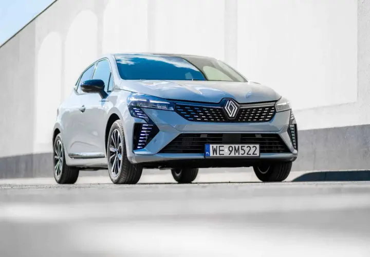 Nowoczesne Renault Clio 2024 w szarym kolorze prezentuje się dynamicznie na tle białej ściany.