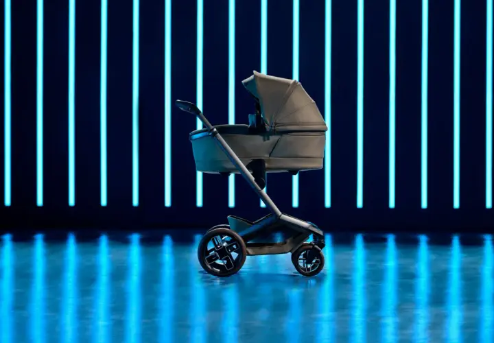 Elegancki wózek dziecięcy Maxi Cosi Fame na tle neonowych, niebieskich świateł.
