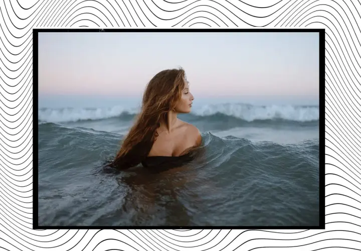 Mujer con cabello largo y ondulado se sumerge en el mar, rodeada de olas que parecen invitar a soñar con olas gigantes.