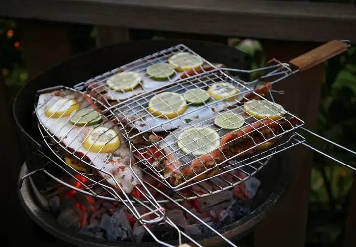 Grilla abborre med citron och lime på en kolgrill. Doften sprider sig i sommarkvällen.