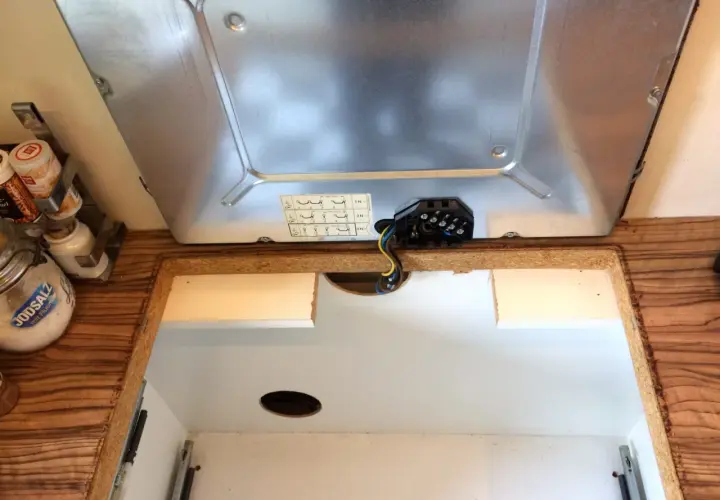 Beim Kochfeld ausbauen wird die elektrische Verbindung gelöst. Kabel und Anschlussklemmen sind sichtbar.