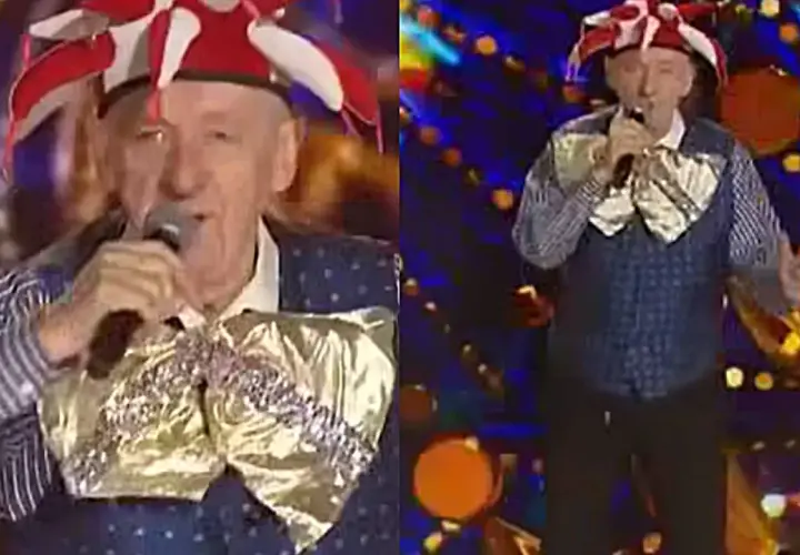 Artysta w stroju błazna śpiewa na scenie. Może to być fragment koncertu z piosenkami Rosiewicza alfabetycznie.