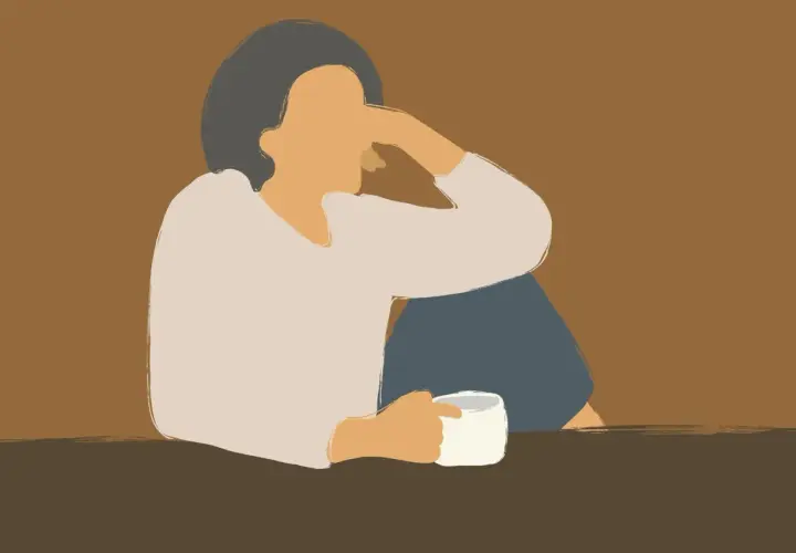 Eine Person sitzt allein mit einer Tasse Kaffee, die Arme um die Knie geschlungen. Die Haltung und der Ausdruck deuten auf eine lieblose Ehe im Alter hin, voller Einsamkeit.