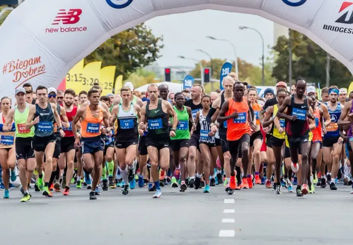 Start maratonu dla amatora. Zawodnicy pod łukiem startowym, tłum kibiców i kamerzystów.