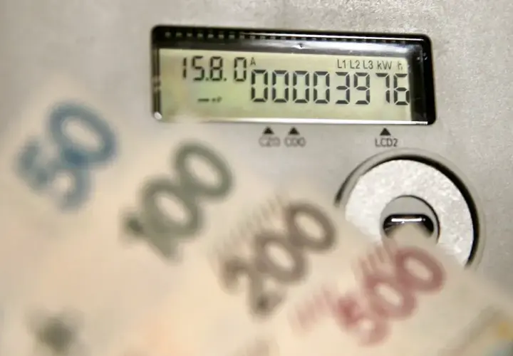 Zbliżają się wysokie rachunki za prąd. Licznik pokazuje zużycie, a banknoty 50, 100, 200, 500 zł sugerują przyszłą cenę prądu za 1 kWh w 2026 roku.