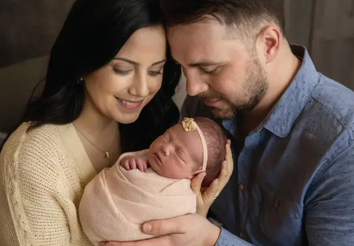 Ciepłe sesje noworodkowe z rodzicami. Mama i tata z czułością tulą swoje maleństwo, tworząc niezapomniane wspomnienia.