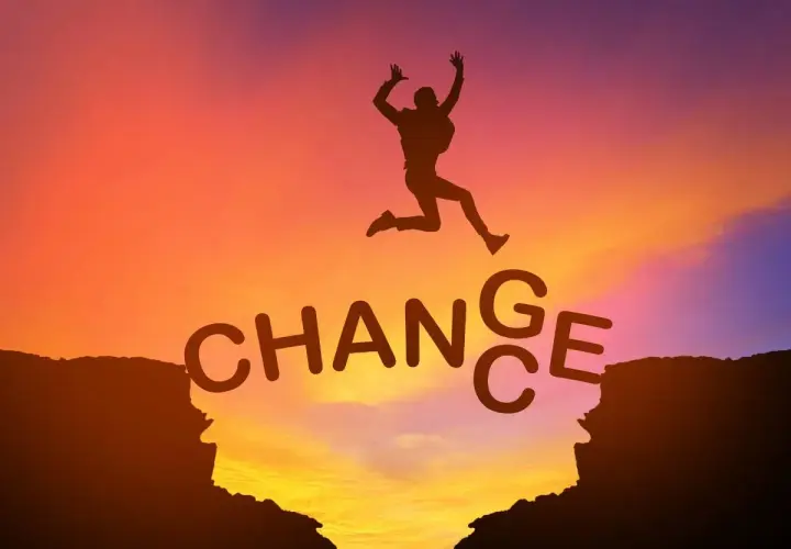 Sylwetka skacze przez przepaść, nad napisem "CHANGE". Jak mówiły Oprah Winfrey cytaty, zmiana jest kluczem do rozwoju.