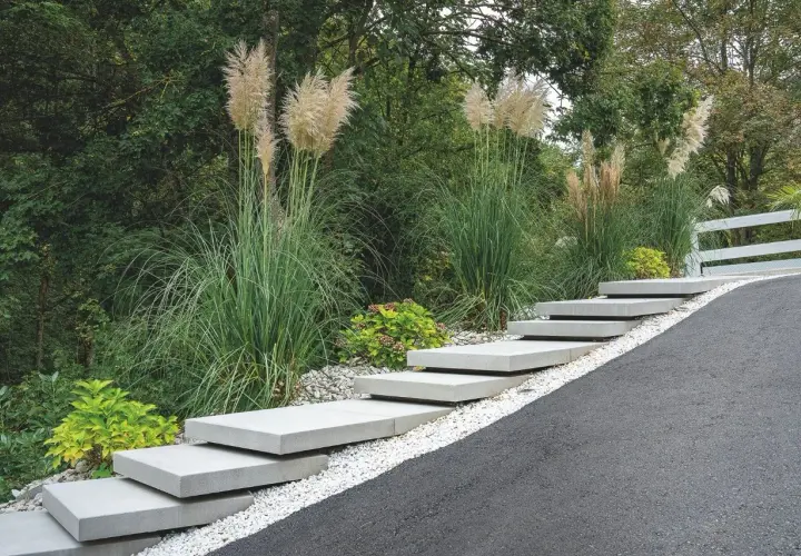 Moderne Treppe aus trockenbeton-Platten, umgeben von Ziergräsern und Kies.