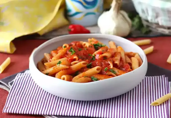 Penne all'arrabiata co to? Pikantny sos pomidorowy z czosnkiem i papryczką chili na makaronie penne, posypane natką pietruszki.