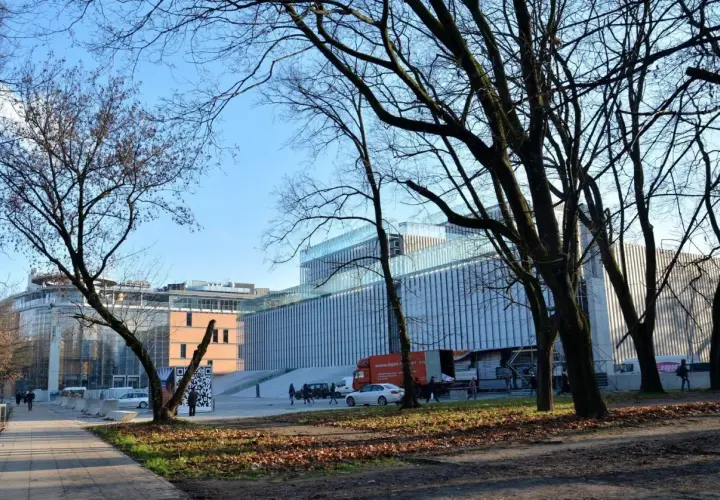 Nowoczesny budynek Centrum Spotkania Kultur na placu teatralnym w Lublinie, otoczony drzewami.