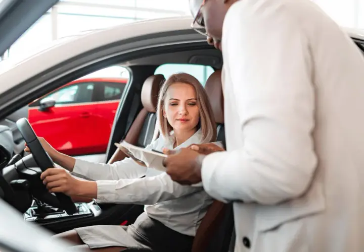 Kobieta za kierownicą nowego auta, sprzedawca omawia warunki fiat leasing.