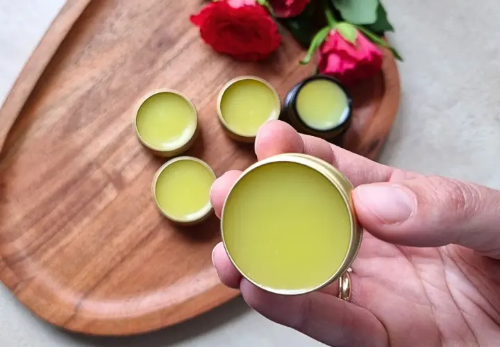 Małe, złote pojemniczki z zielonym balsamem, idealne do domowej produkcji perfum. Różane akcenty dodają uroku.