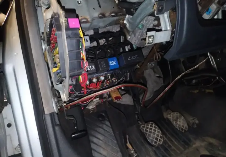 Widok na skrzynkę z bezpiecznikami i przekaźnikami w Audi A4 B6. Widać kolorowe bezpieczniki i kable.
