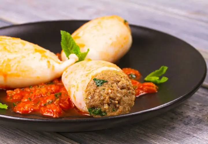 Calamari ripieni in friggitrice ad aria, serviti con salsa rossa e menta fresca. Un piatto gustoso e leggero.