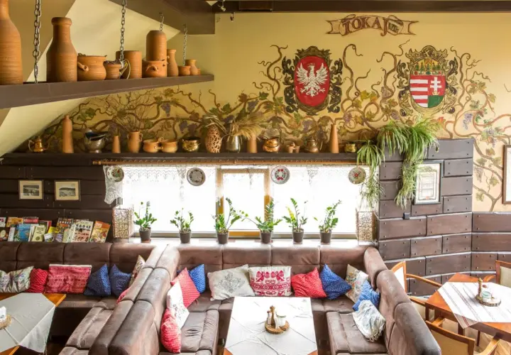 Wnętrze tokaj restauracja węgierska menu. Wygodne kanapy, ozdobne malowidła na ścianie i ceramiczne naczynia tworzą przytulną atmosferę.
