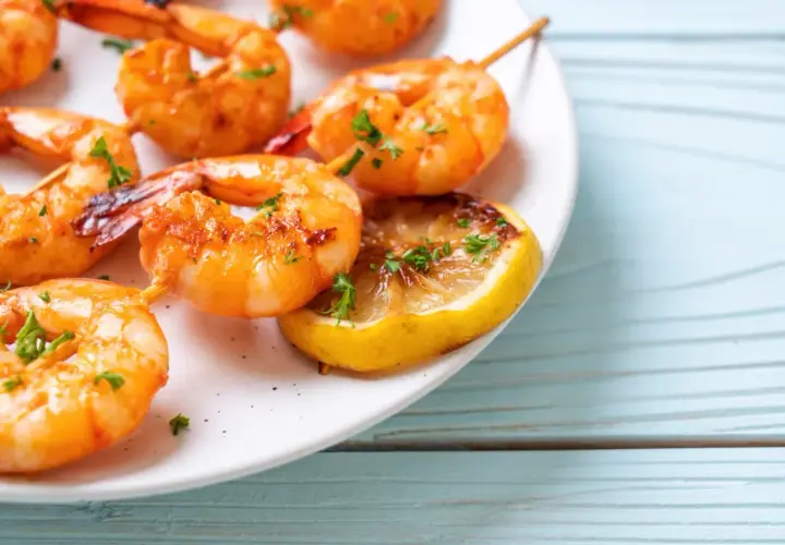 Soczyste krewetki z airfryer, podane z grillowaną cytryną i posypane natką pietruszki, kuszą apetycznym wyglądem.