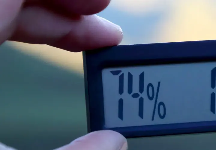 En digital hygrometer visar 74%, vilket indikerar hög luftfuktighet inomhus.