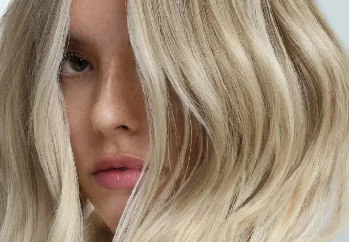 Rostro de mujer con cabello rubio platino, un ejemplo de que es matizar el pelo para un tono perfecto.