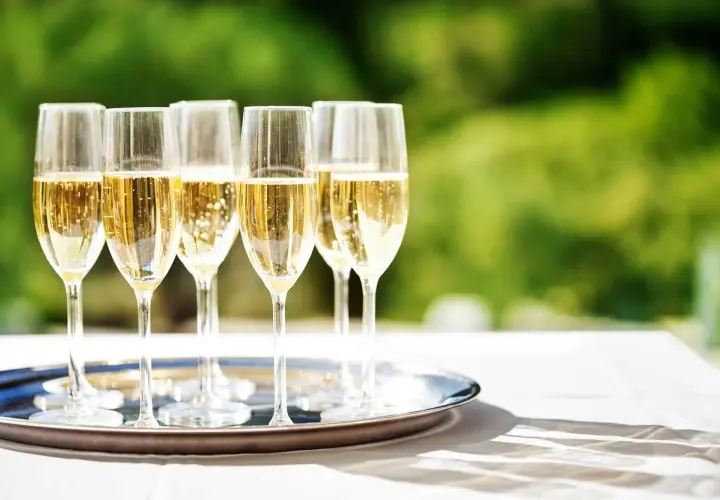 Six flûtes de champagne pétillant sur un plateau argenté, prêtes pour le dessert. Quel champagne pour le dessert ?