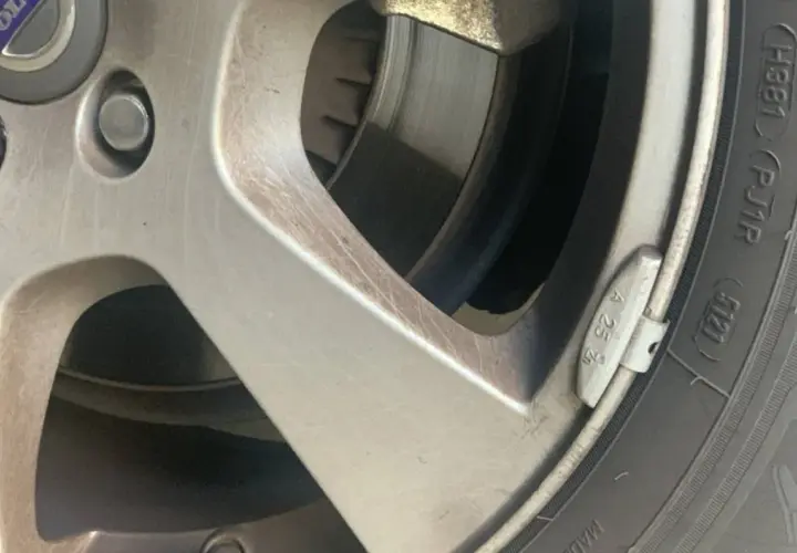 Detalle de una llanta de coche con un plomo de equilibrado de ruedas visible.