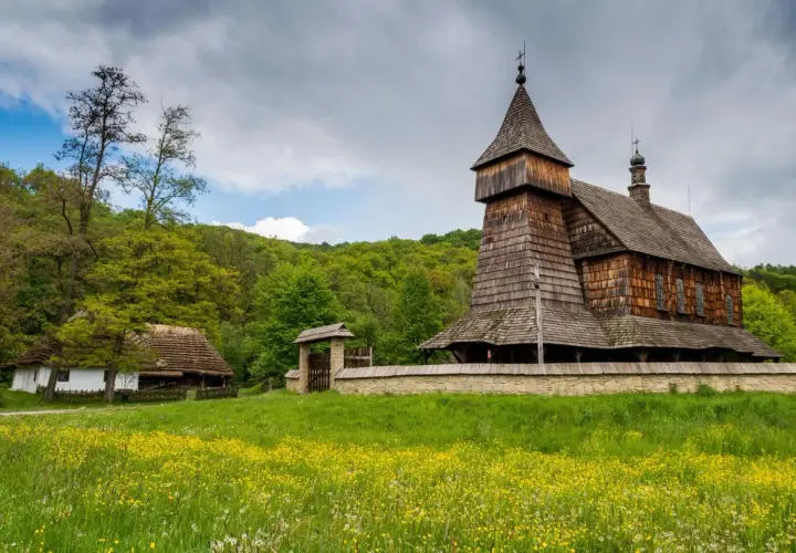 Drewniana cerkiew i chałupa na tle zielonych wzgórz. Największy skansen w Polsce zaprasza do podróży w czasie.