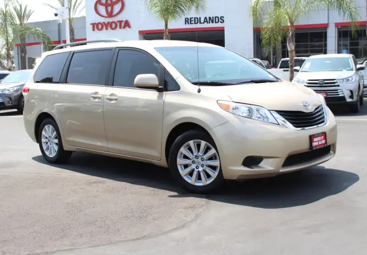 Złoty minivan Toyota Sienna zaparkowany przed salonem Toyoty.