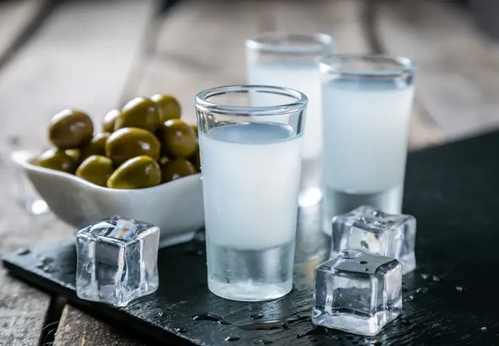 Trzy kieliszki z mlecznym ouzo, kostki lodu i miseczka oliwek. Tak pije się ouzo, by poczuć smak Grecji.