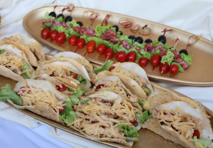 Un buffet froid mariage avec des tacos garnis de poulet, salade et fromage râpé, et des brochettes de tomates, olives et salami.