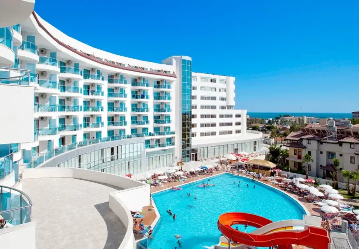 Hotel Narsia Resort: biały, nowoczesny budynek z niebieskimi balkonami i basenem z atrakcjami wodnymi. Słoneczny dzień, wakacyjna atmosfera.