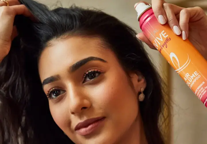Mujer con pelo graso usa spray de champú seco para dar volumen y frescura.