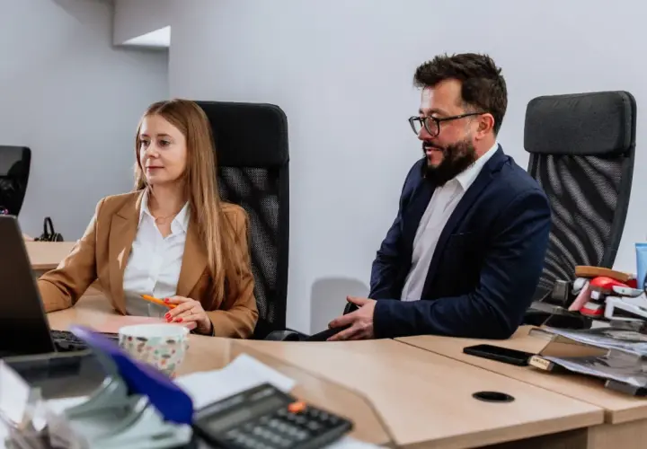 Kobieta i mężczyzna w biurze pracują przy komputerach.
