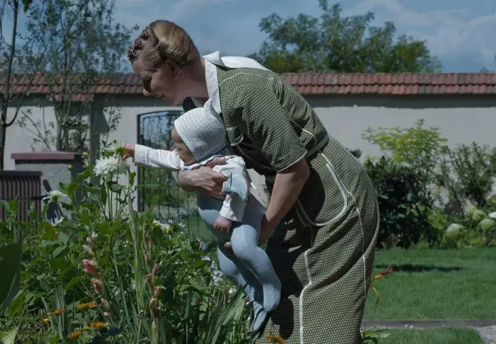 Kobieta w zielonej sukience pokazuje dziecku kwiaty. Scena jak z mądrych filmów wartych obejrzenia, pełna czułości i piękna natury.