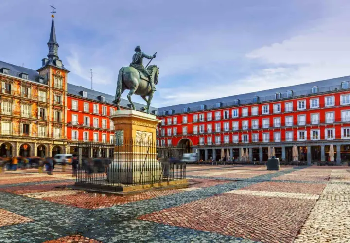 Plaza Mayor de Madrid, con estatua ecuestre y edificios rojos. Imagina llegar en tren santiago madrid y ver esta maravilla.