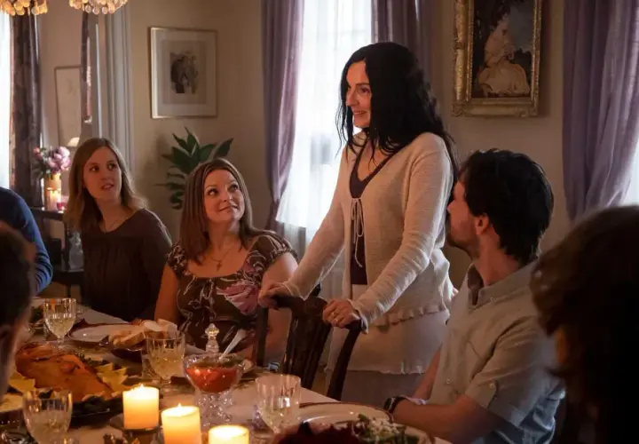 En familj samlas runt ett middagsbord, kanske för en högtidlig stund som i Knutby (tv-serie). Ljusen flimrar och maten är framdukad.