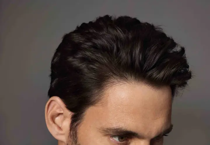 Primer plano de un hombre con mas cantidad de pelo oscuro y peinado hacia atrás, mostrando su oreja y parte de su rostro.