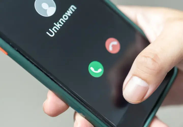 Dłoń trzyma smartfon z ekranem pokazującym nieznane połączenie. Zastanawiasz się, jak zastrzec numer jednorazowo?