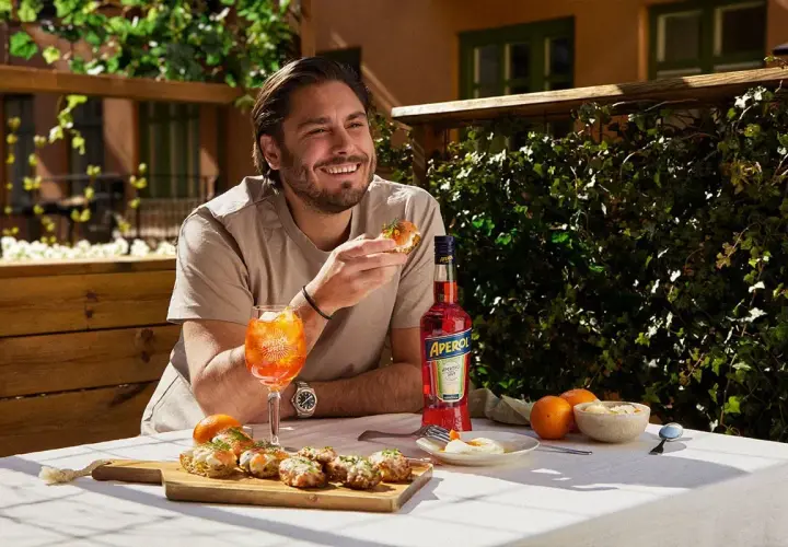 Man njuter av en Aperol Spritz och tilltugg utomhus.