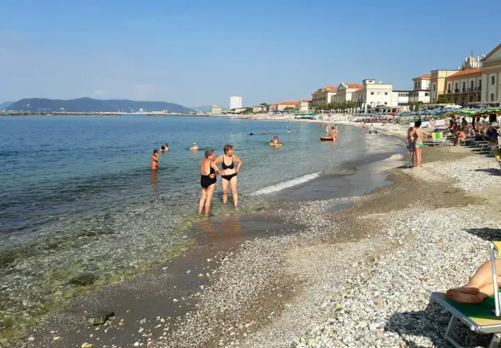 Plage de Massa, Italie. Des baigneurs profitent de l'eau claire et du soleil sur cette plage de galets animée.