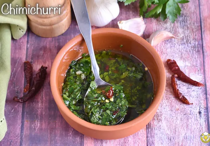 Salsa chimichurri fresca in ciotola di terracotta, con aglio, peperoncino secco e prezzemolo.