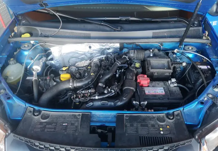 Motor de Dacia Sandero GLP con mangueras de gas y batería. Posibles problemas de instalación o mantenimiento.