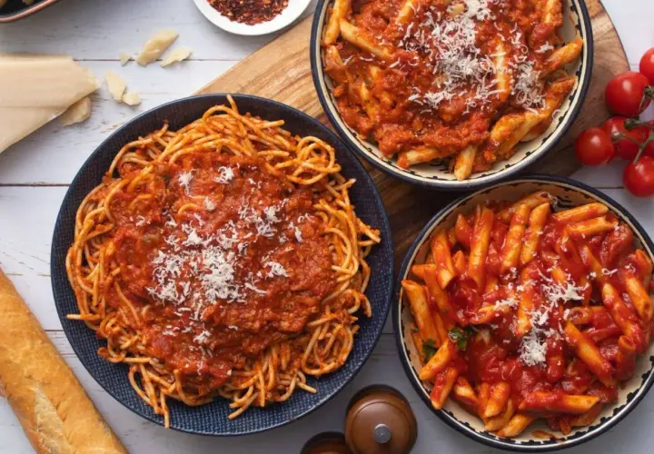 Pyszny obiad bez mięsa: spaghetti i penne w sosie pomidorowym, posypane parmezanem. Idealne dla wegetarian.