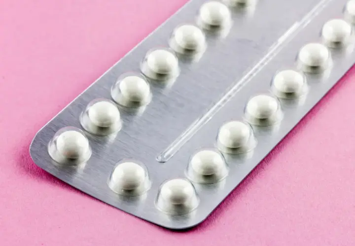 Eine Blisterpackung mit weißen Pillen auf rosa Untergrund. Die Pillen sind bereit, um sie durchzunehmen.