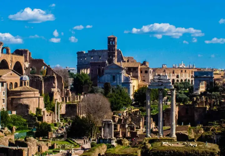 Il Foro Romano, un'istantanea di un viaggio a Roma 48h. Rovine antiche, il Colosseo e il cielo azzurro con nuvole bianche.