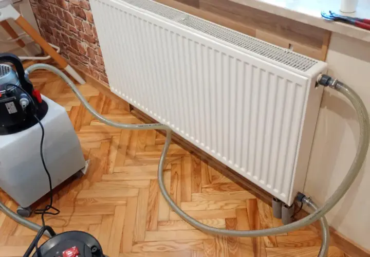 Profesjonalne płukanie instalacji grzewczej w Warszawie. Sprzęt do czyszczenia podłączony do grzejnika.