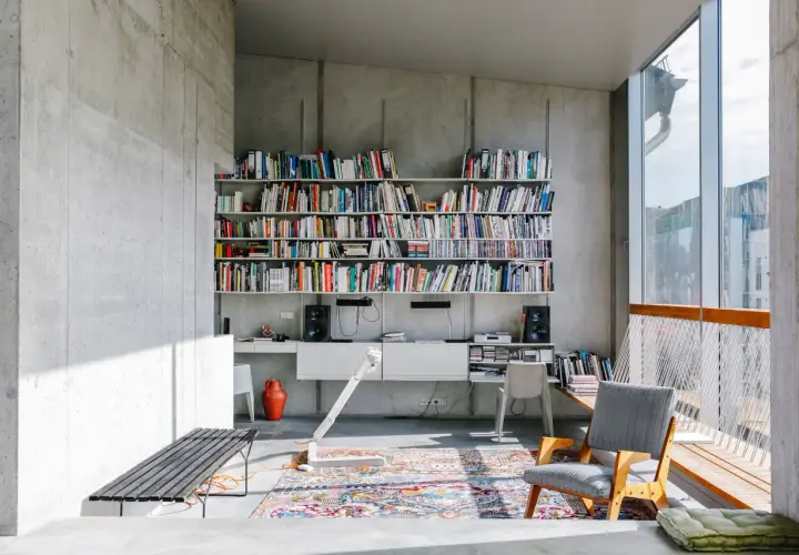Ein bunter, detailreicher Perserteppich bildet einen warmen Kontrast zur kühlen Betonarchitektur und zeigt, wie man einen Perserteppich modern kombinieren kann.